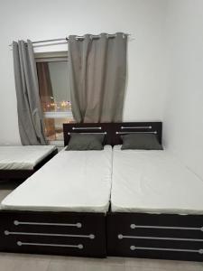 two twin beds in a room with a window at Tabs Dubai Hostel in Dubai