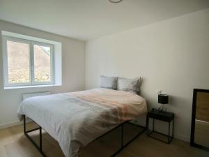 a white bedroom with a bed and a window at Maison de campagne - Chez Félicien in Recologne-lès-Rioz