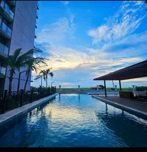 einen Pool mit Palmen neben einem Gebäude in der Unterkunft apartamento con vista al mar in Santa Marta