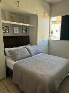 ein Schlafzimmer mit einem Bett mit Kissen und einem Fenster in der Unterkunft Encanto Parangaba in Fortaleza + 14 Fotos