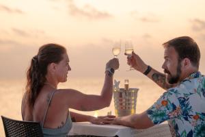 a man and woman sitting at a table with wine glasses at Nika Inn Himandhoo in Himandhoo 