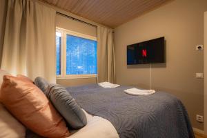 a bedroom with a bed with a tv on the wall at Kaisantien Kirsti, Vuokatti in Vuokatti