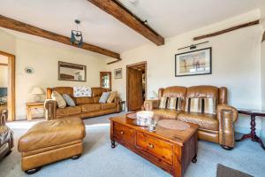 a living room with leather furniture and a coffee table at 18th Century Farmhouse, England Wales Border, Breathtaking Views in Oswestry