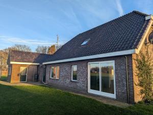 a red brick house with a large window at Vrijstaande Landelijke Woning in Slagharen