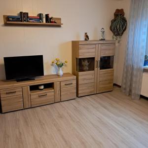 a living room with a tv and a wooden entertainment center at Ferienhaus Kornew OG in Dornum +21 photos