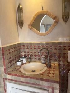 a bathroom with a sink and a mirror at Riad Dar Dayana in Essaouira