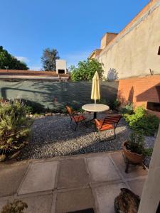 a patio with two chairs and a table with an umbrella at La casita del colibri in Córdoba