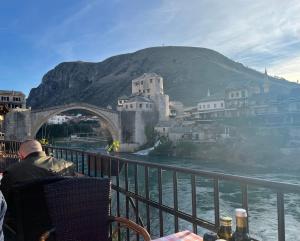 a man sitting in a chair in front of a bridge at Villa Anja Apartments in Mostar