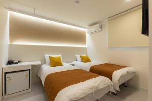 two beds in a small room with yellow pillows at Friends in Seoul