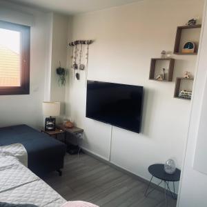 a bedroom with a flat screen tv on a white wall at F3 à mimizan plage in Mimizan-Plage