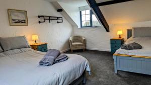 a bedroom with two beds and two lamps and a chair at Yetland Farm Holiday Cottages in Combe Martin