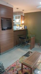 un salon avec une télévision, une table et des chaises dans l'établissement Flat Life Resort com serviço diário de limpeza, à Brasilia