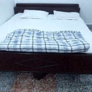 a bed with white sheets and pillows on it at Shree Dhaam Homestay in Faizābād