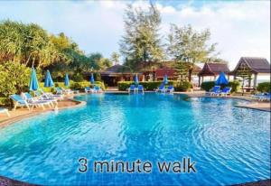 a large swimming pool with blue chairs and umbrellas at Lanta Cozy House 01 in Ko Lanta