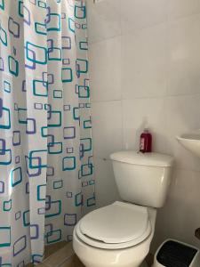 a bathroom with a toilet and a shower curtain at Hostal y Camping Villa Guadua Tayrona in Santa Marta