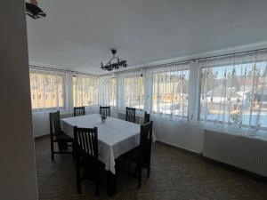 a dining room with a table and chairs and windows at Pensiunea Valea Dorului in Fundăţica