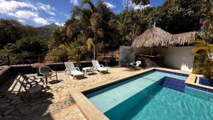 a swimming pool with chairs and a house at hotel Tayrona Angel Lodge cerca a la entrada el zaino parque nacional tayrona in El Zaino