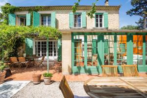 Mas des Olivades - Ferme Provençale - Piscine في بيرنيه لو فونتينز: منزل به نوافذ خضراء وفناء