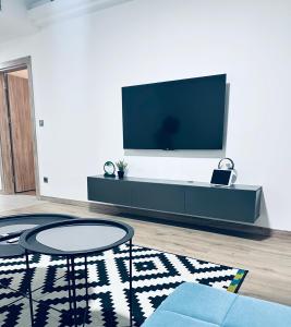 Una sala de estar con un televisor de pantalla plana en una pared. en Regina's Sky View Apartment 32nd floor, en Skopje