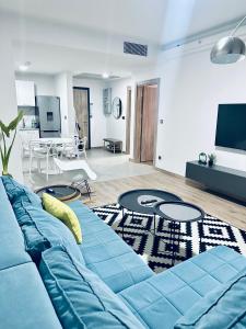 Una sala de estar con un sofá azul y una mesa. en Regina's Sky View Apartment 32nd floor, en Skopje