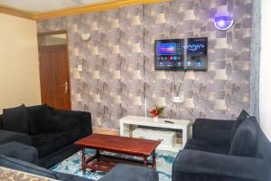 a living room with two couches and a tv on a wall at TWO BEDROOM Delamere Apartment in Mombasa