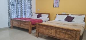 a bedroom with two beds and a window at Balkis homestay in Madikeri +8 photos