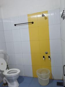a bathroom with a toilet and a yellow wall at Balkis homestay in Madikeri