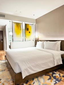 a large white bed in a bedroom with two windows at Rockwell View King Suites in Manila