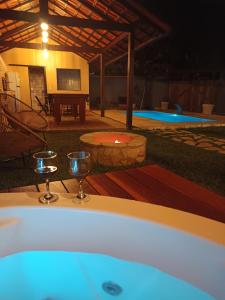 a bath tub with wine glasses next to a pool at Meu canto em Lumiar in Nova Friburgo