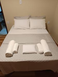 a bed with white towels and pillows on it at Meu canto em Lumiar in Nova Friburgo