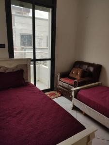 a room with two beds and a couch and a window at شقة مغربية تقليدية في وسط المدينة in Ksar el Kebir