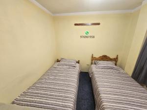 two beds in a room with a green clock on the wall at HOSPEDAJE ALVARADO - DOBLE - 101 - Bueno Bonito y Barato in Cajamarca