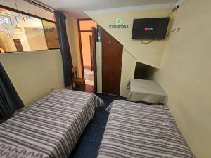 two beds in a room with a tv on the wall at HOSPEDAJE ALVARADO - DOBLE - 101 - Bueno Bonito y Barato in Cajamarca