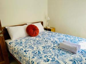 a bed with a red pillow and two towels on it at Tio Homestay in Praya