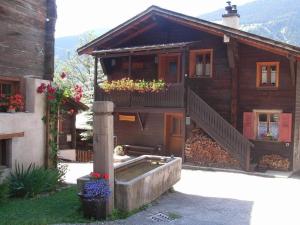 a house with a staircase and a balcony with flowers at Alpenrose Aletsch Landschaftspark Binntal in Grengiols