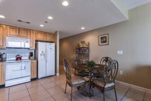 cocina con mesa, sillas y nevera blanca en Splash Ocean-front Luxury Two-bedroom Beach Condo, en Panama City Beach