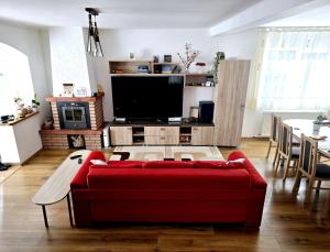 un soggiorno con un divano rosso e una TV di Casa La Buni a Buşteni