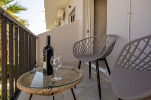 a bottle of wine and a glass on a table on a balcony at Iviskos - Adults Only in Laganas