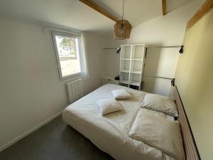 a bedroom with a bed with white sheets and a window at Maisonnette Le Galet Jaune in Bretignolles-sur-Mer +9 photos