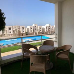 a balcony with a table and chairs and a large window at 2BR Amwaj Terrazza & Piscina in Marsa Matruh