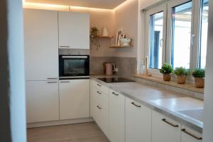 a white kitchen with a sink and a microwave at Stylish Forest View - Apartment in Augsburg