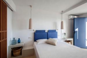 a bedroom with a large bed with a blue headboard at Oneiro Rooms Kythnos in Kanala
