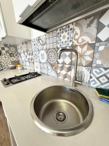 a stainless steel sink in a kitchen with tiles at Aria case vacanze - Orzo in Favignana +65 photos