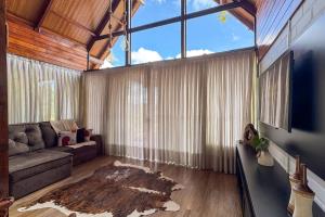 a living room with a couch and a large window at Chalé Mirante dos Anjos in Rodeio