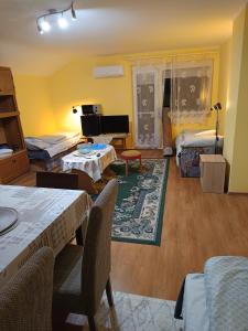 sala de estar con 2 camas, mesa y sillas en Dékány vendégház, en Mezőhegyes