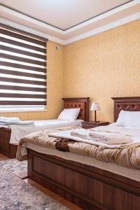 two beds in a bedroom with a window at Major Guest House in Fergana