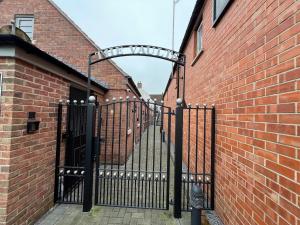 a black iron gate with a brick wall at Glastonbury Hidden Passage, Split Level 1 Bedroom Apt in Glastonbury