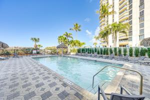 a swimming pool at a resort with chairs and trees at Oceanfront Marco Island Escape with Beach Access! in Marco Island