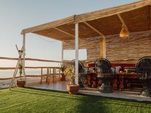 a pavilion with chairs and a table on the beach at Tamraght Blue House in Tamraght Ou Fella