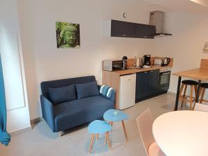 a living room with a blue couch and a kitchen at Duplex Moderne de 33m2 - Elegance et Confort in Doudeville +7 photos